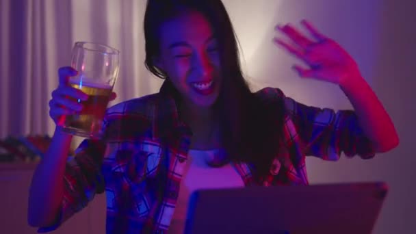 Young Asia lady drinking beer having fun happy moment disco neon night party event online celebration via video call in living room at home. Social distancing, quarantine for coronavirus prevention. - Footage, Video