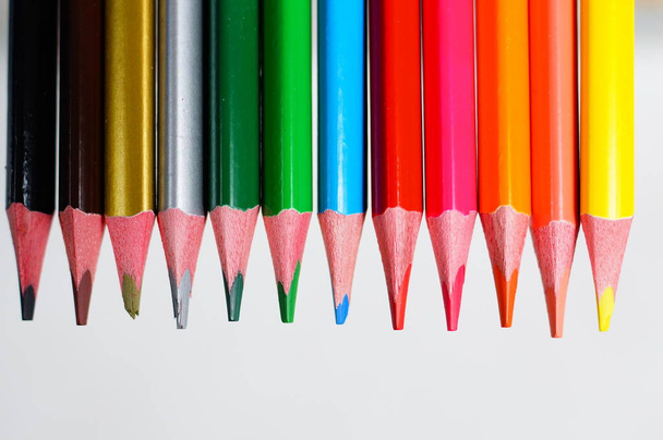Kleurrijke potloden - gelijkmatig gerangschikt in een rij over de gehele breedte van het frame, in close-up. - Foto, afbeelding