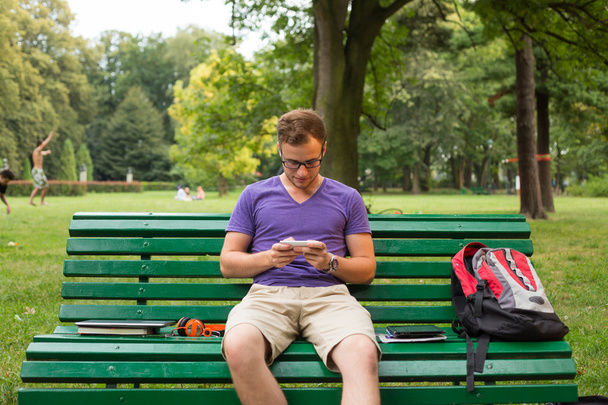 Student with phone on bench - Φωτογραφία, εικόνα