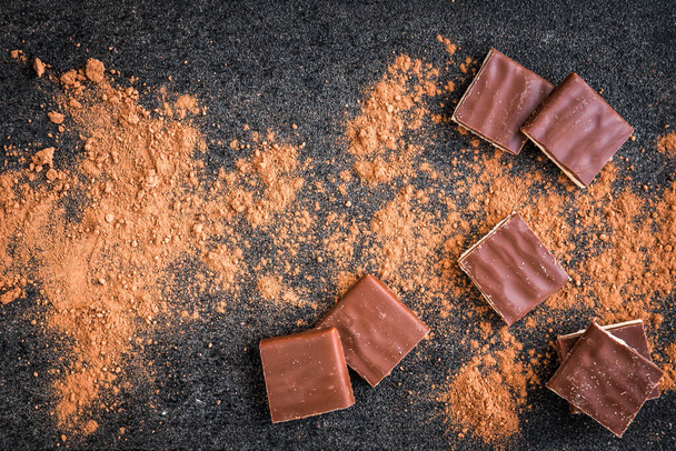 Milk chocolate bar chocolate chips and cocoa on black background - Φωτογραφία, εικόνα