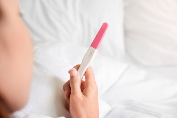 Unhappy young asian woman holding pregnancy test showing a negative result in her bedroom, wellness and healthy concept, infertility problem,Selective focus. - Photo, Image