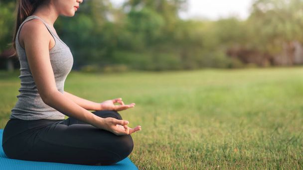 Asian woman meditating and sit in the lotus pose at park, Healthy and Yoga Concept,Mind-body improvements concept, Selective focus, Copy space. - Φωτογραφία, εικόνα