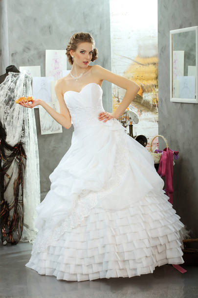 meisje in een trouwjurk maakt montage in de kleding designstudio - Foto, afbeelding