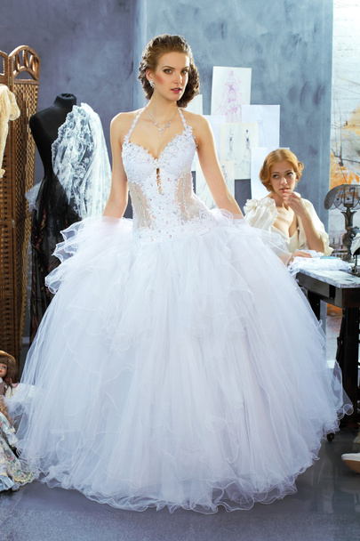 Девушки в свадебном платье делают примерку в студии дизайна одежды
 - Фото, изображение