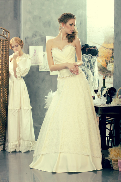 Le ragazze in un abito da sposa fanno montaggio nello studio di design di abbigliamento
 - Foto, immagini