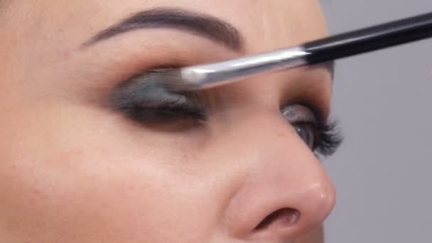 Krásná velkolepá mladá žena v aplikuje make-up na její tvář se speciálním štětcem před zrcadlem - Záběry, video
