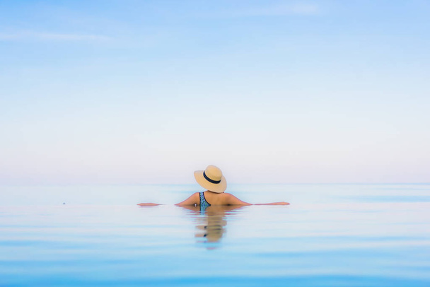 Retrato hermosa joven mujer asiática relajarse sonrisa ocio alrededor de la piscina al aire libre casi playa de mar en vacaciones de viaje - Foto, Imagen