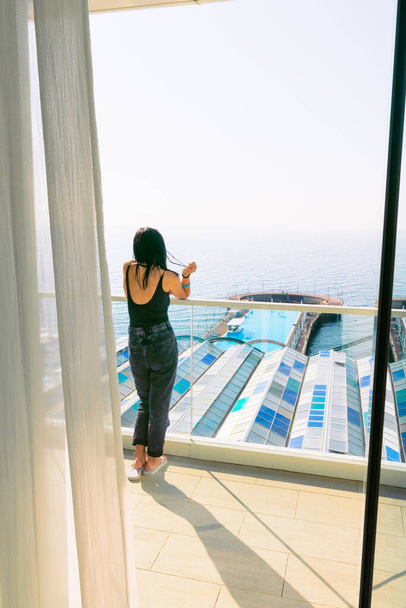 18. října,2020. Shekvetili. Georgia. paragraphs apgh pětihvězdičkový hotel luxusní pokoj balkon výhled na moře s ženským zákazníkem stojící a hledá bazén oblasti. - Fotografie, Obrázek
