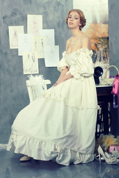 Mulher bonita em vestido vintage está no estúdio de design de roupas
 - Foto, Imagem