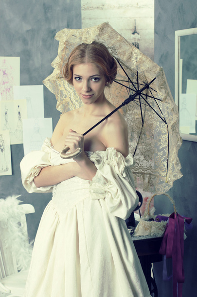Hermosa mujer en vestido vintage está en estudio de diseño de ropa
 - Foto, Imagen