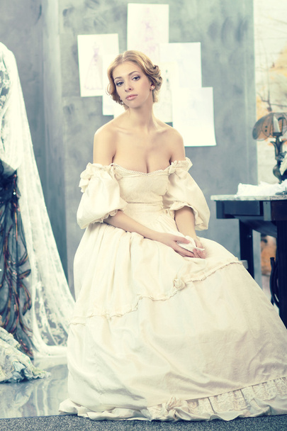 Красивая женщина в винтажном платье находится в студии дизайна одежды
 - Фото, изображение