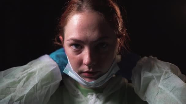 Genç bayan doktor koruyucu beyaz bir takım elbise ve tıbbi bir maske giyer. Koronavirüsle mücadele kavramı - Video, Çekim