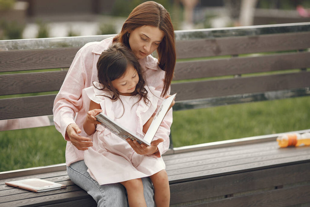 Mother with daughter reading a book in the city - Foto, imagen