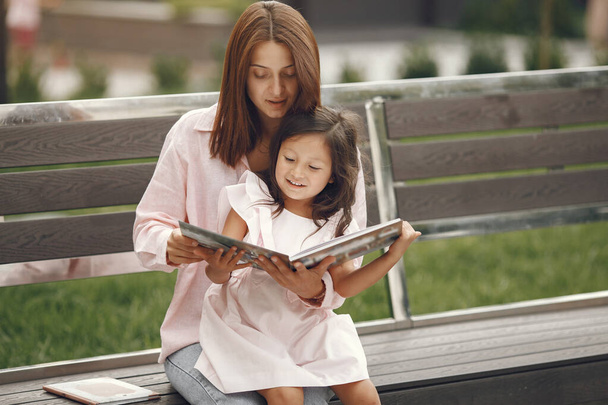 Mother with daughter reading a book in the city - Фото, зображення