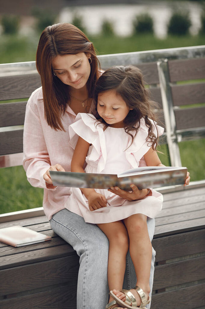 Mother with daughter reading a book in the city - 写真・画像