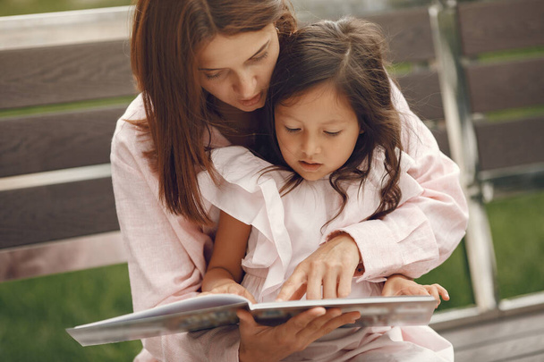 Mother with daughter reading a book in the city - Photo, Image