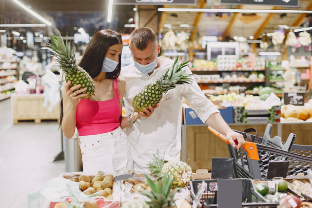 Couple in a medical masks in a supermarket - Foto, afbeelding