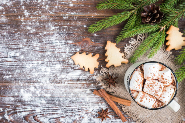 マシュマロ、スパイス、クリスマスジンジャークッキー、モミの枝や暗い木製の背景にコーンとホットチョコレートのマグカップ。テキストのスペースをコピーします。クリスマス壁紙カード. - 写真・画像