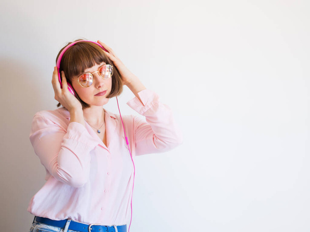 Jeune femme heureuse en chemise rose avec écouteurs - Photo, image