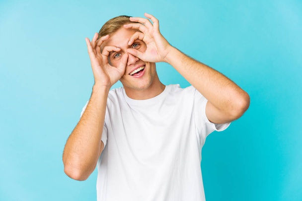 Young caucasian handsome man showing okay sign over eyes - Photo, Image