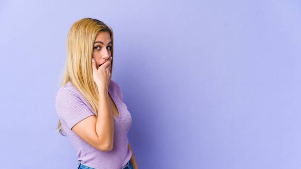 Junge blonde kaukasische Frau nachdenklich Blick auf eine Kopie Raum bedeckt Mund mit der Hand. - Foto, Bild