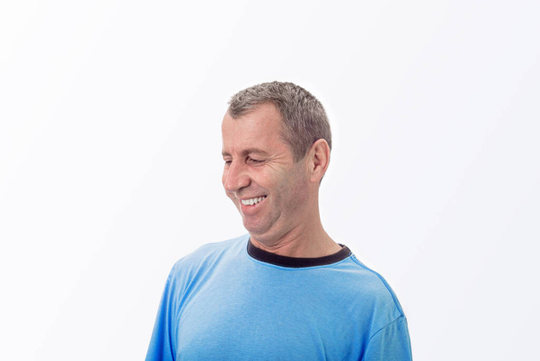 Щасливий чоловік середнього віку посміхається в повсякденній футболці ізольовано на білому тлі. Портрет веселого літнього чоловіка, який посміхається ізольовано на білому тлі. Середньовіччя Позитивні емоції
. - Фото, зображення