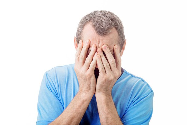 Portret rozczarowanego mężczyzny w średnim wieku, zakrywający twarz dłońmi, patrzący w dół przygnębiony. Seniorzy cierpiący na załamanie emocjonalne i depresję na białym tle. - Zdjęcie, obraz