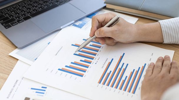 Accounting businessmen are calculating income-expenditure and analyzing real estate investment data, He works on a desk has graphs and calculators with laptop, Financial and tax systems concept. - Photo, Image