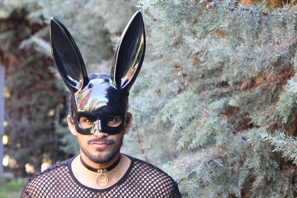 ritratto ravvicinato di bel giovanotto in maglia a rete e maschera coniglietto nero all'aperto - Foto, immagini