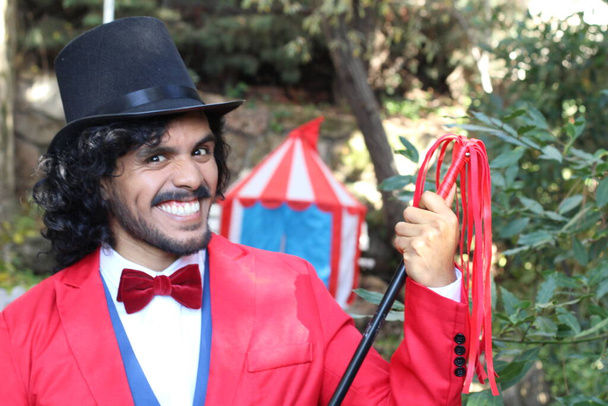 Sirk çadırının önünde kırmızı kostümlü yakışıklı sirk sihirbazının portresi. - Fotoğraf, Görsel