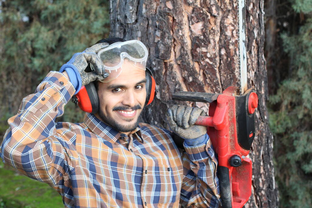 retrato de cerca del joven guapo con bigote leñador de trabajo con máquina de sierra - Foto, imagen