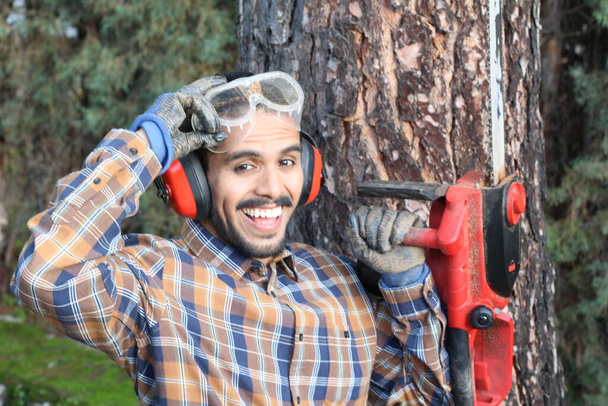 Nahaufnahme Porträt eines gutaussehenden jungen Mannes mit Schnurrbart, der Holzfäller mit Sägemaschine arbeitet - Foto, Bild