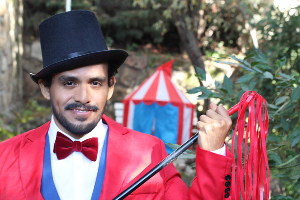 портрет красивого циркового мага в красном костюме перед цирковой палаткой - Фото, изображение