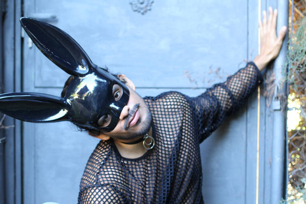 közeli kép egy jóképű fiatalemberről hálóingben és fekete nyuszi maszkban a szabadban - Fotó, kép
