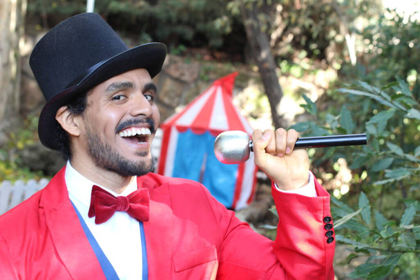 Sirk çadırının önünde kırmızı kostümlü yakışıklı sirk sihirbazının portresi. - Fotoğraf, Görsel