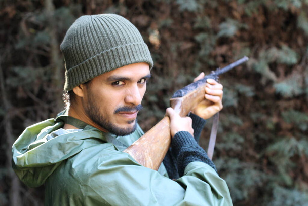 Outdoor portret van een jonge jager met geweer in het bos - Foto, afbeelding
