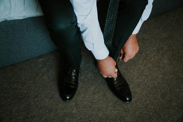 A closeup shot of a groom tying his shoes on the wedding day - Foto, Bild