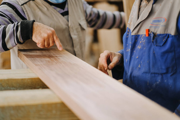 A closeup shot of two carpenters discussing the design of wood - Valokuva, kuva