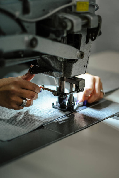 A vertical closeup shot of a female operating an industrial sewing machine - Fotó, kép