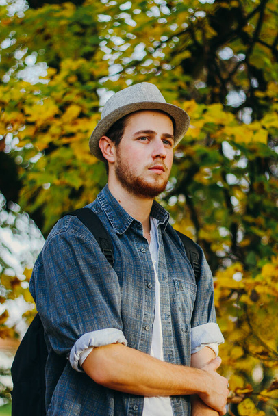 A vertical selective focus shot of an attractive guy in an autumn park - Foto, afbeelding