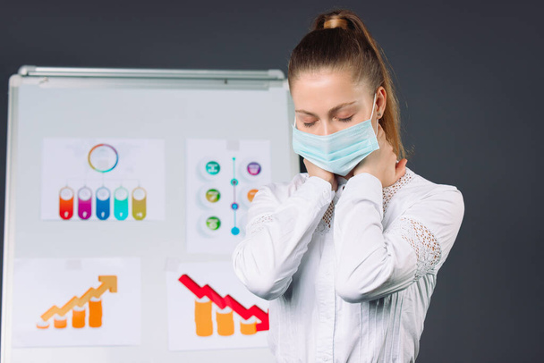 Tired businesswoman wearing a white shirt and a medical mask after a presentation. Pandemic and doing business concept. High quality photo - Фото, зображення