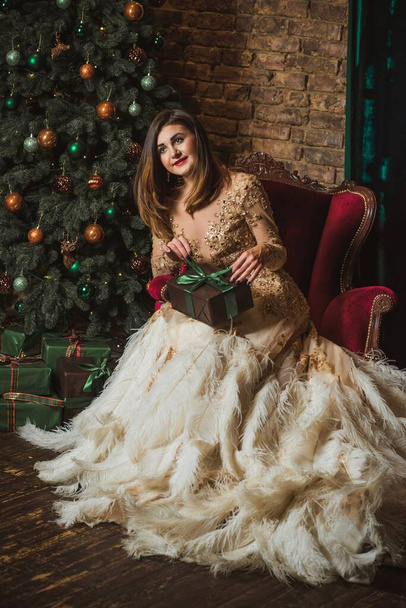  Christmas Holidays, Arabic woman in evening gorgeous dress. Pretty nice lady at Holly eve. Woman in beautiful golden sparkle dress with feathers  - Фото, зображення