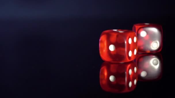 Movimiento lento de balanceo cubos de juego en la mesa negra.Rolling dados de casino rojo - Metraje, vídeo