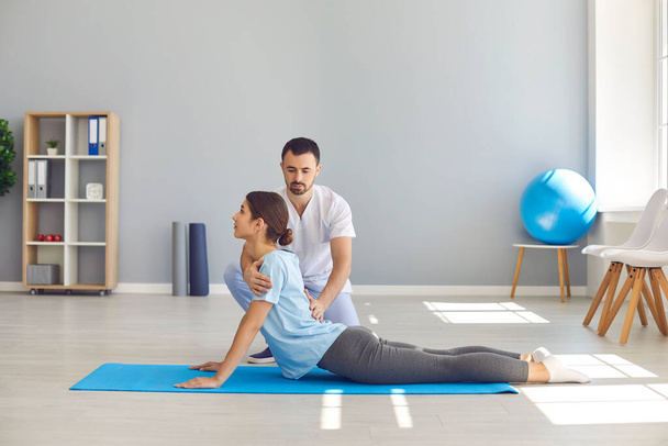 Женщина делает упражнения для восстановления гибкости спины во время физиотерапии после спортивной травмы - Фото, изображение
