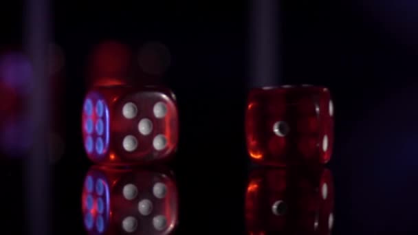 Movimiento lento de balanceo cubos de juego en la mesa negra.Rolling dados de casino rojo - Metraje, vídeo