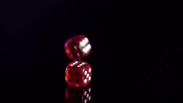 Movimento lento de rolar cubos de jogo na mesa preta.Rolamento de dados de casino vermelho - Filmagem, Vídeo