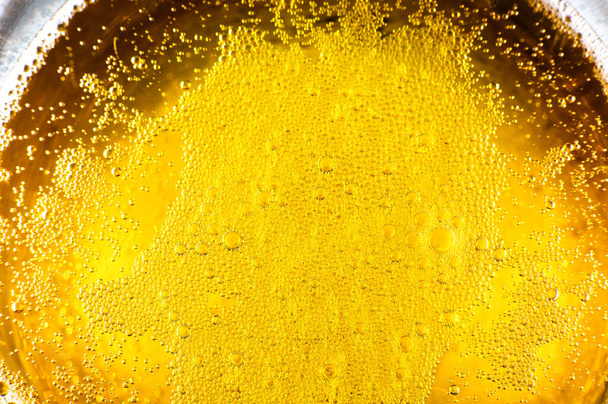 Flüssiges goldgelbes Benzin blubbert im Hintergrund auf Bier- oder Sektgläsern. Nahaufnahme, Makroaufnahme. - Foto, Bild