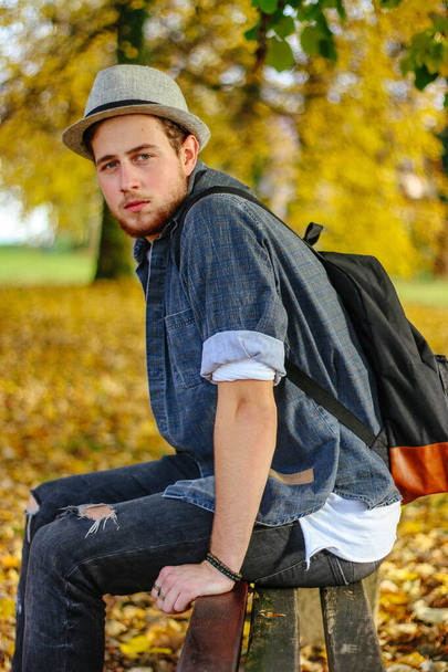 A vertical selective focus shot of an attractive guy in an autumn park - Valokuva, kuva