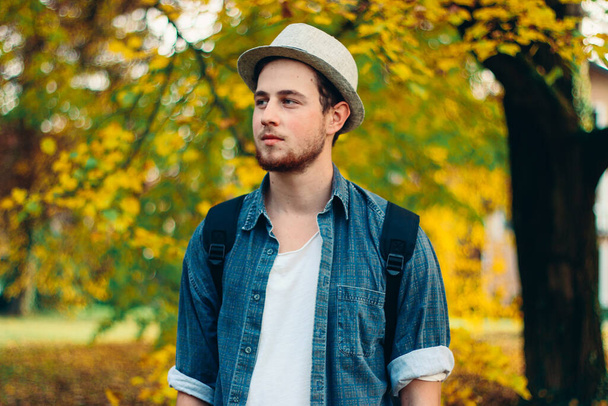 A selective focus shot of an attractive guy in an autumn park - Foto, immagini