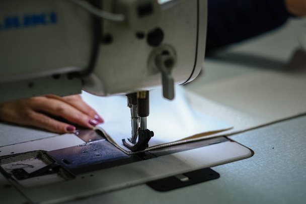 A closeup shot of a female operating an industrial sewing machine - Foto, Bild